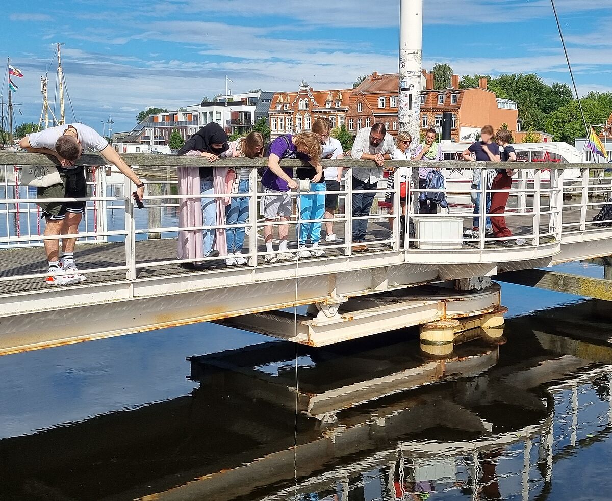 Schüler messen die elektrische Leitfähigkeit an der Brücke am Museumshafen in Greifswald