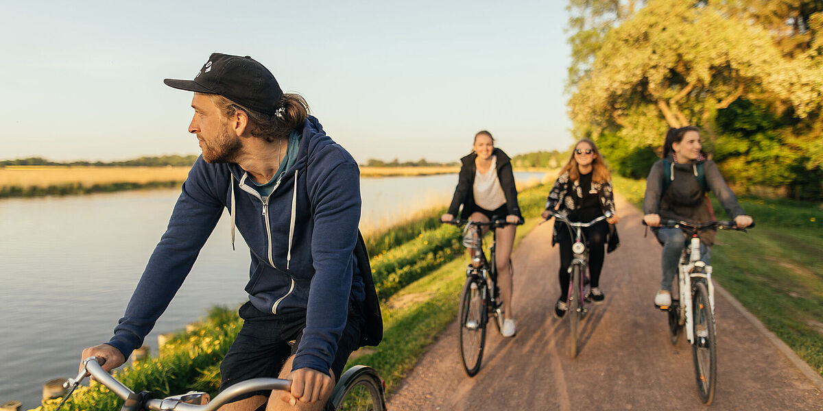 Eine Gruppe Radfahrer*innen auf dem Treidelpfad am Flüsschen Ryck.